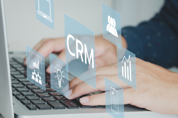 Hands typing on laptop with visual of CRM above