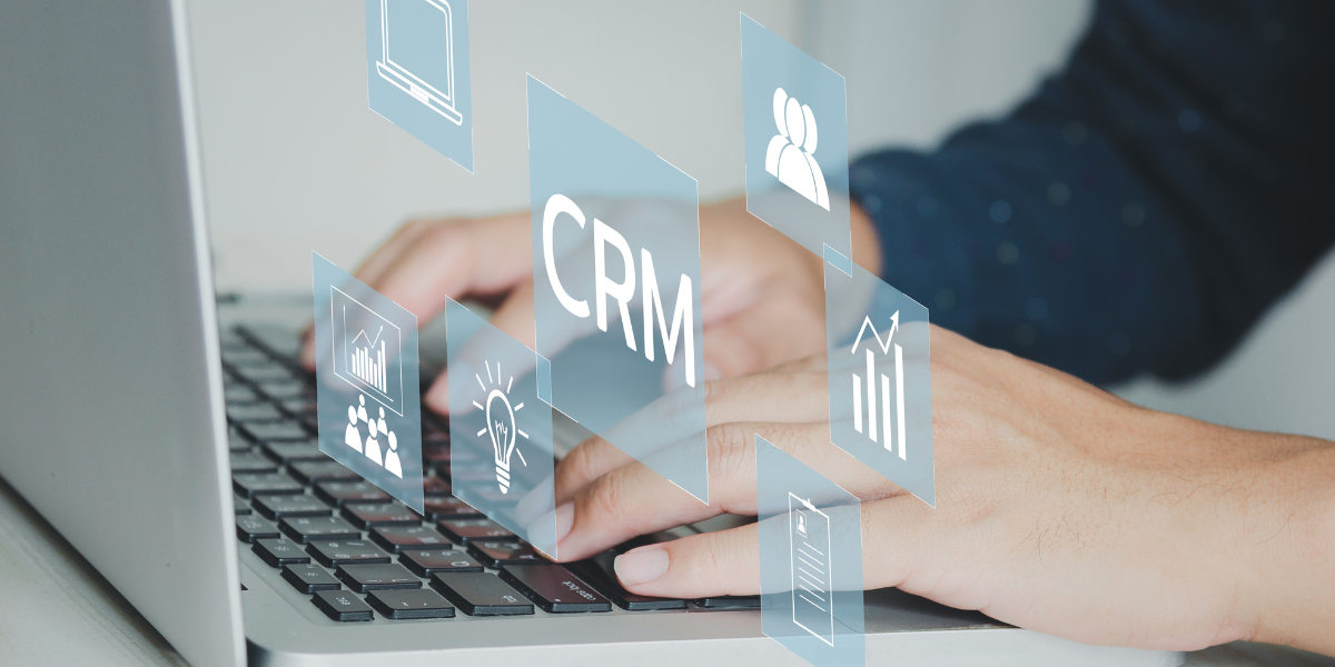 Hands typing on laptop with visual of CRM above
